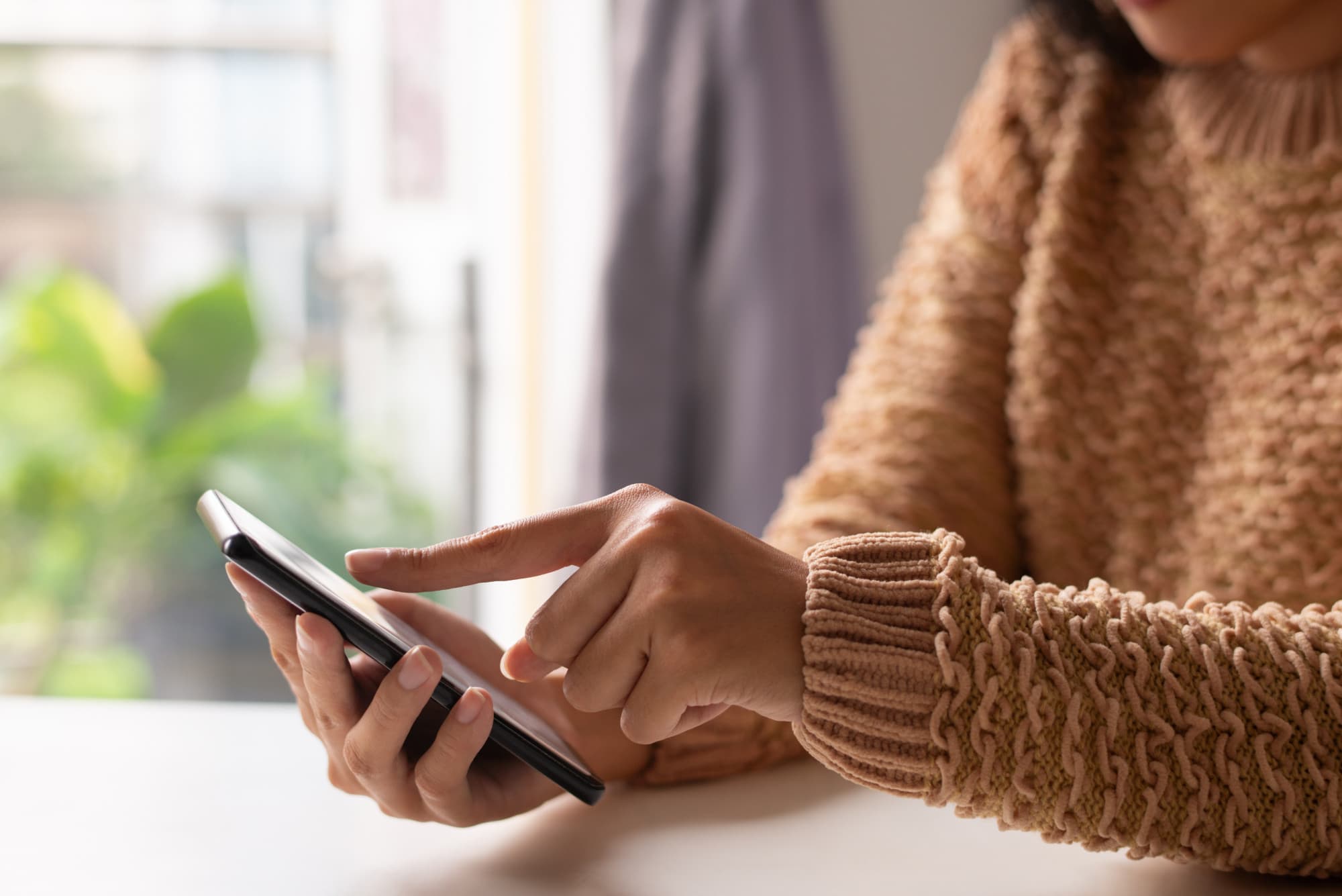 Young adult signing up for KreditBuilder on their phone in a dorm or first apartment, natural light